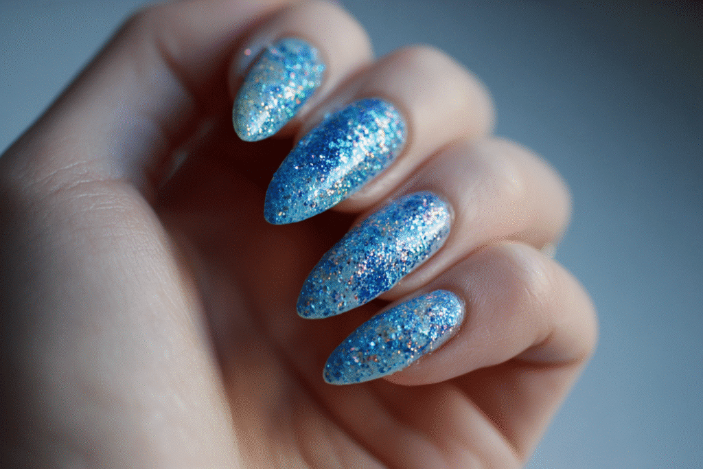 Hand with long almond-shaped gel nails in sparkling pool blue glitter, perfect for summer vibes