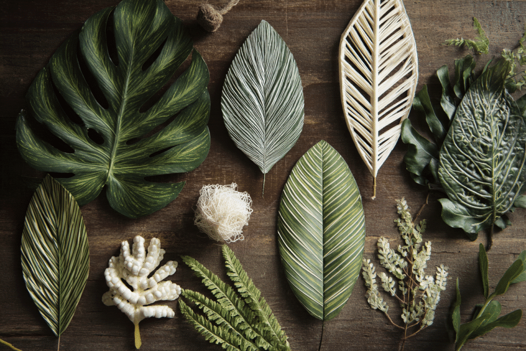 Flat lay of assorted tropical leaves and greenery on a rustic wooden background, natural textures